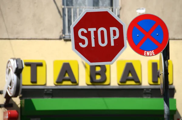 Egy dohánybolt bejárata, piros STOP tábla és zöld háttér.